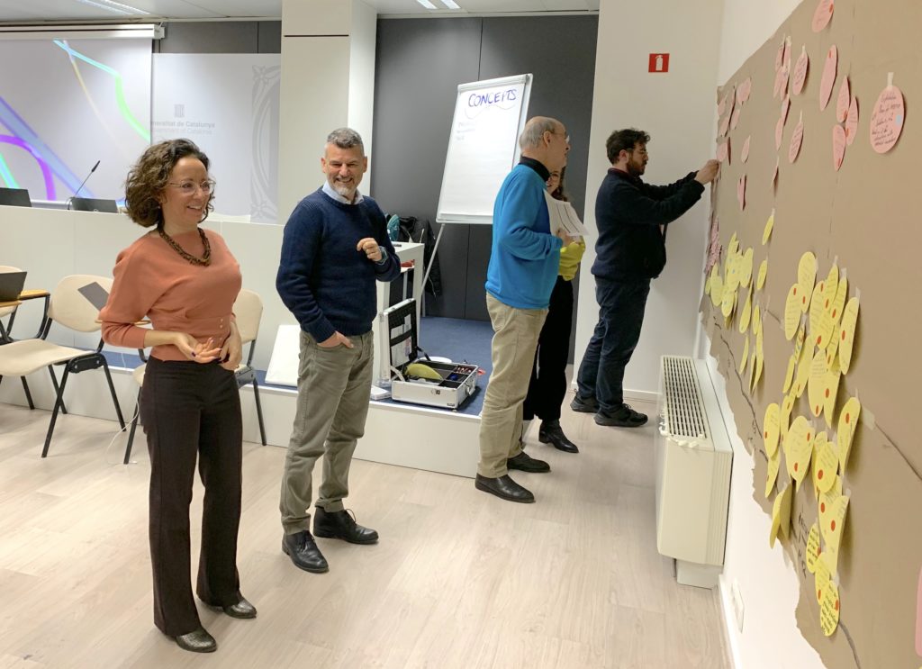 Photo of people smiling and sticking papers to a wall during a workshop event
